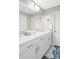 Bathroom with white cabinets, large mirror, and blue patterned rug on the dark flooring at 8917 Yates Dr, Westminster, CO 80031