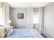 Bright bedroom featuring a patterned blue bedspread, neutral paint, and large window with curtains at 8917 Yates Dr, Westminster, CO 80031