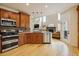 Open-concept kitchen featuring wood cabinetry, stainless steel appliances, and hardwood floors, flowing into a cozy living area at 9478 Burgundy Cir, Highlands Ranch, CO 80126