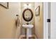 A quaint powder room shows a pedestal sink, decorative mirror, and neutral wall paint at 9478 Burgundy Cir, Highlands Ranch, CO 80126