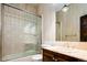 Cozy bathroom featuring a glass shower, vanity and decorative wallpaper at 2409 E Cedar Ave, Denver, CO 80209
