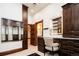 A dressing area featuring dark wood cabinetry, shelving, drawers, and a mirrored vanity and doorway to bath at 2409 E Cedar Ave, Denver, CO 80209