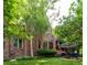 Charming brick home with manicured lawn, mature trees, and outdoor seating area at 2409 E Cedar Ave, Denver, CO 80209