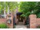 Inviting brick home entrance with decorative gate, lush trees, and manicured garden beds at 2409 E Cedar Ave, Denver, CO 80209