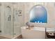 Bathroom with tiled walk-in shower and tub by an arched window at 16200 Quarry Hill Dr, Parker, CO 80134