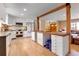 Bright kitchen with white cabinets, hardwood floors, a wooden breakfast bar, and modern appliances at 3885 Hoyt St, Wheat Ridge, CO 80033