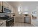 Bright kitchen with stainless steel appliances, white cabinets, and an open view to the living area at 4437 Cornish Way, Denver, CO 80239