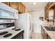 View of kitchen with microwave, stove, refrigerator, wooden cabinets and patterned wallpaper at 1805 W Stoll Pl, Denver, CO 80221