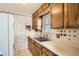 View of kitchen with wooden cabinets, window above sink and patterned wallpaper at 1805 W Stoll Pl, Denver, CO 80221