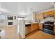 Kitchen with wood cabinets, stainless steel appliances, and a view into the living room at 9673 Ironton St, Commerce City, CO 80022