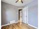 A bedroom with grey walls, hardwood floors, a ceiling fan, and a doorway to the hallway at 1780 Oswego St, Aurora, CO 80010