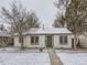 Charming home featuring a white brick exterior, green door, and snow-dusted lawn at 1780 Oswego St, Aurora, CO 80010