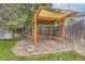 Landscaped backyard with wooden pergola, stone base, wood fence, grass and mature shade trees at 8750 Redwing Ave, Littleton, CO 80126