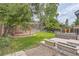 Landscaped backyard with mature trees, a fire pit, and a concrete patio at 8750 Redwing Ave, Littleton, CO 80126
