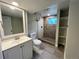 Bathroom with new shower, stone tile, built-in shelves, and white sink and cabinets at 15908 E Flora Pl, Aurora, CO 80013