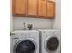 Functional laundry room with overhead cabinets, utility hookups, and modern washer/dryer set at 8962 E Otero Pl, Centennial, CO 80112