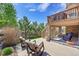 A backyard patio with stone-covered pillars and outdoor seating, complemented by a well-manicured lawn and lush trees at 24316 E Ottawa Ave, Aurora, CO 80016