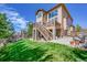 A spacious backyard features a wooden deck, stone pillars, stairs, green grass, and an outdoor patio at 24316 E Ottawa Ave, Aurora, CO 80016