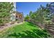 A well-manicured backyard with lush green grass, a stone-clad patio, a wooden fence, and mature trees at 24316 E Ottawa Ave, Aurora, CO 80016