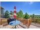 Outdoor deck featuring a table with umbrella, grill, and wooden railing overlooking lush greenery and blue sky at 24316 E Ottawa Ave, Aurora, CO 80016