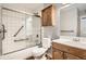 Compact bathroom features a shower-tub combo with sliding glass doors and a wooden vanity at 3663 S Sheridan Blvd # J12, Denver, CO 80235