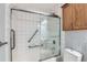 Bathroom with a shower over tub with sliding glass doors, white tile surround and hand rails at 3663 S Sheridan Blvd # J12, Denver, CO 80235