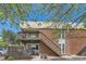 A charming apartment building with a brick facade and a wooden staircase leading to the second floor at 3663 S Sheridan Blvd # J12, Denver, CO 80235