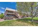 The building includes a wooden deck with access stairs to an outdoor green space and shade tree at 3663 S Sheridan Blvd # J12, Denver, CO 80235