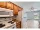 Functional kitchen featuring white appliances, wood cabinetry, and laminate countertops at 3663 S Sheridan Blvd # J12, Denver, CO 80235