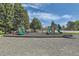 A sunny community playground with slides and climbing features, surrounded by trees and a chain-link fence at 3663 S Sheridan Blvd # J12, Denver, CO 80235