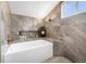 Bathroom featuring a soaking tub, sleek gray tile, and modern lighting at 7591 S Reed Ct, Littleton, CO 80128
