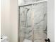 Modern bathroom shower with marble tile and glass door enclosure at 7591 S Reed Ct, Littleton, CO 80128