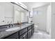 Bright bathroom featuring double sinks, a granite countertop, and an elegant vanity at 7591 S Reed Ct, Littleton, CO 80128
