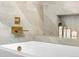 Close up of a bathtub with gold fixtures and a built in shelf at 7591 S Reed Ct, Littleton, CO 80128