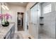 Bright bathroom with a granite countertop vanity, walk-in shower, and a glimpse into the laundry area at 16578 E 111Th Pl, Commerce City, CO 80022