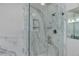 Close-up of the sleek glass shower with built-in shelving, and marble-patterned wall paneling at 13456 Via Varra # 406, Broomfield, CO 80020