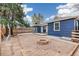 View of backyard featuring gravel, a stone fire pit, a wooden fence, and blue siding house at 2718 S Hazel Ct, Denver, CO 80236