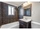 Bathroom with dark tiled shower and walls, white fixtures, and wood vanity at 2718 S Hazel Ct, Denver, CO 80236