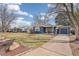 Inviting home with a well-manicured lawn, mature trees, and a driveway leading to the garage at 2718 S Hazel Ct, Denver, CO 80236