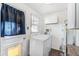 Bright laundry room featuring a white washer and dryer, upper cabinet, and natural light from the window at 2718 S Hazel Ct, Denver, CO 80236