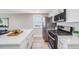 Modern kitchen with stainless steel appliances, bright white cabinetry, and an island with seating open to the living area at 4507 W 2Nd Ave, Denver, CO 80219