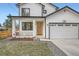 Attractive home with white siding, covered porch, craftsman railing, orange front door, and two-car garage at 11885 W Katherine Ave, Lakewood, CO 80401