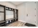 Mudroom featuring wooden floors, built-in storage, and a sleek white door at 11885 W Katherine Ave, Lakewood, CO 80401