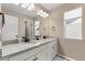Bathroom featuring a double vanity with granite countertop, framed mirror, and modern fixtures at 15100 Gaylord St, Thornton, CO 80602