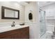 Well-lit bathroom with a dark wood vanity, framed mirror, and glass-enclosed shower stall at 6537 S Brentwood Way, Littleton, CO 80123