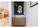 Stylish powder room featuring a wood vanity, black accent wall, and decorative oval mirror at 3363 W 32Nd Ave, Denver, CO 80211