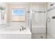 Bright bathroom with a large soaking tub, a glass shower, and white tile at 7137 S Vandriver Way, Aurora, CO 80016