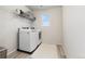 Bright laundry room with modern washer and dryer, ample shelving, and wood-look flooring at 7137 S Vandriver Way, Aurora, CO 80016
