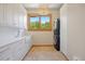 Bright laundry room with a large window, stackable washer/dryer, white cabinets, and a farmhouse sink at 786 International Isle Dr, Castle Rock, CO 80108