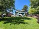 Expansive backyard featuring lush lawn, mature trees, and deck, perfect for outdoor entertaining at 8296 S Reed St, Littleton, CO 80128